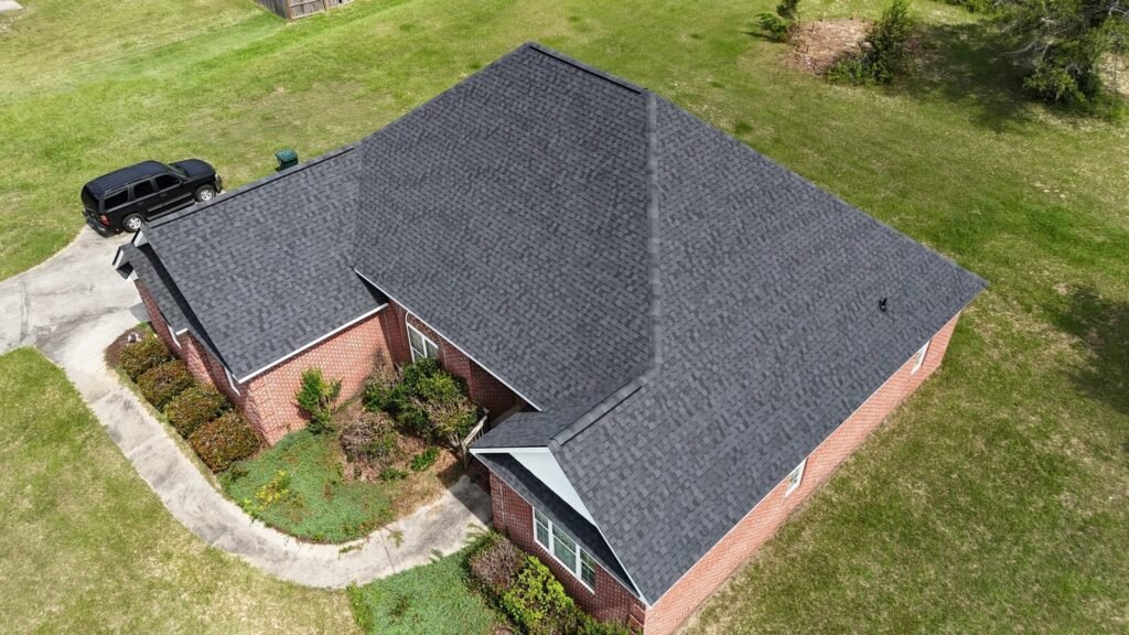 Drone view of a finished dark architectural shingle roof on a brick home