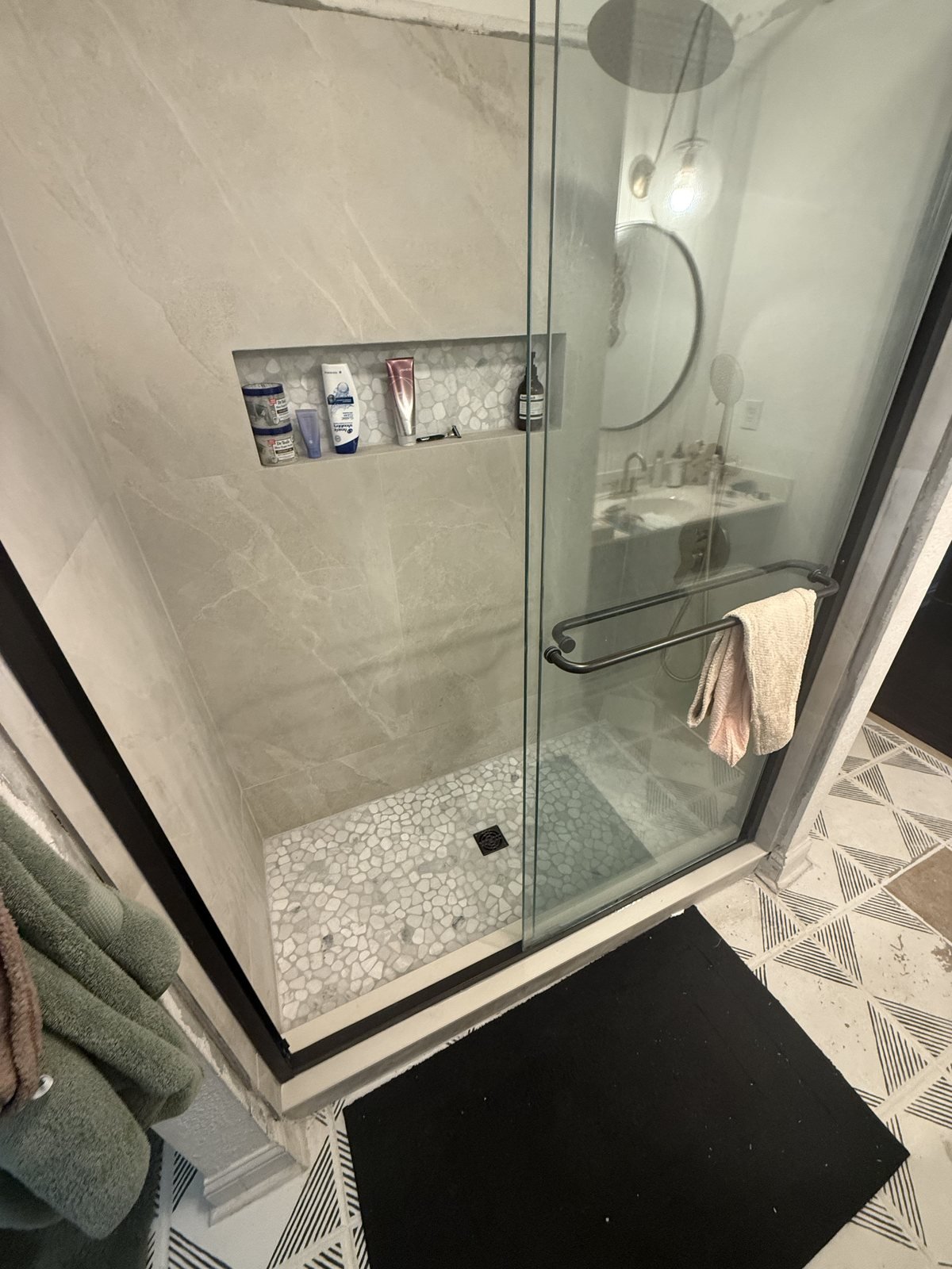 Finished walk-in shower with a glass door, tile walls and a tile floor