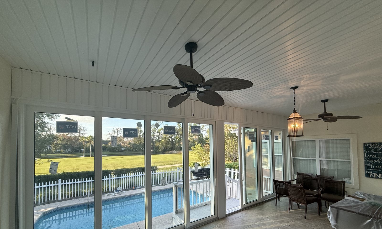 Finished sunroom with a wall of windows, a tile floor and ceiling fans